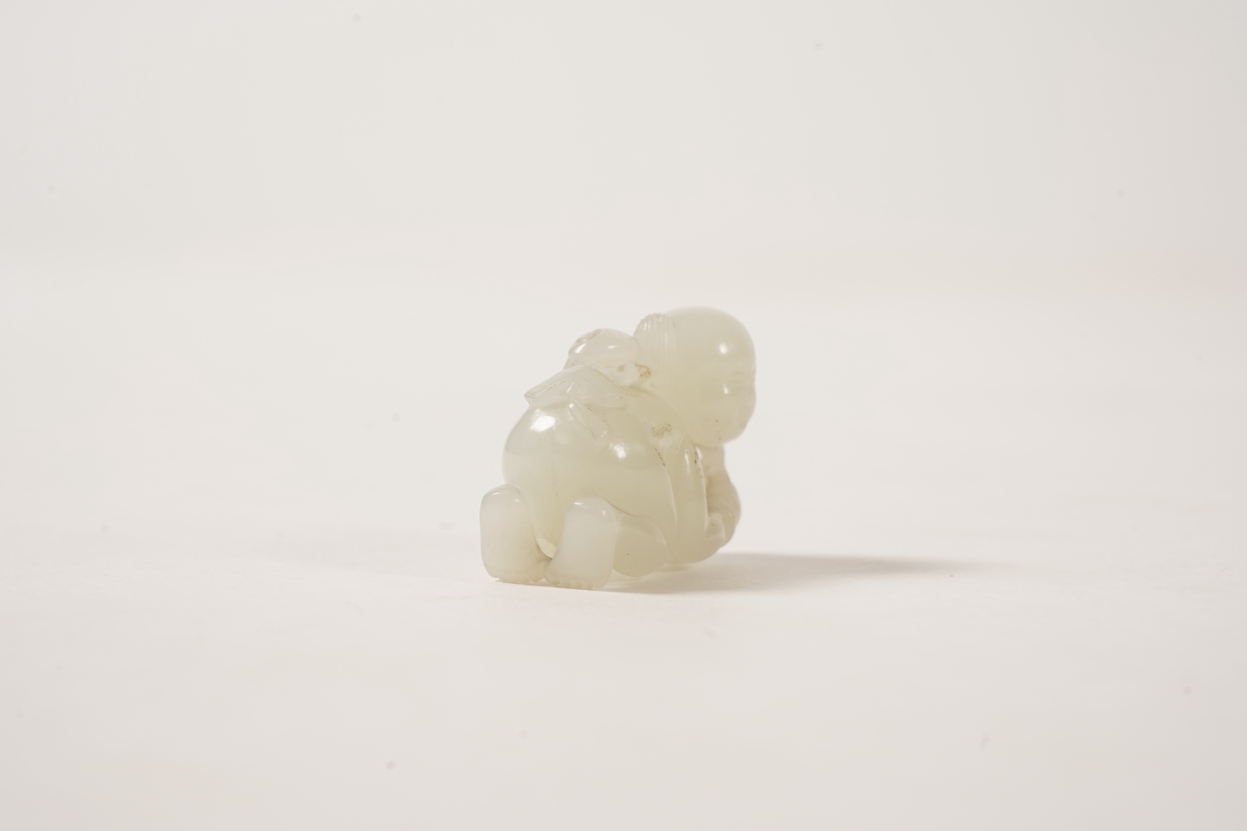 A Chinese white jade figure of a crouching boy, 19th/20th century